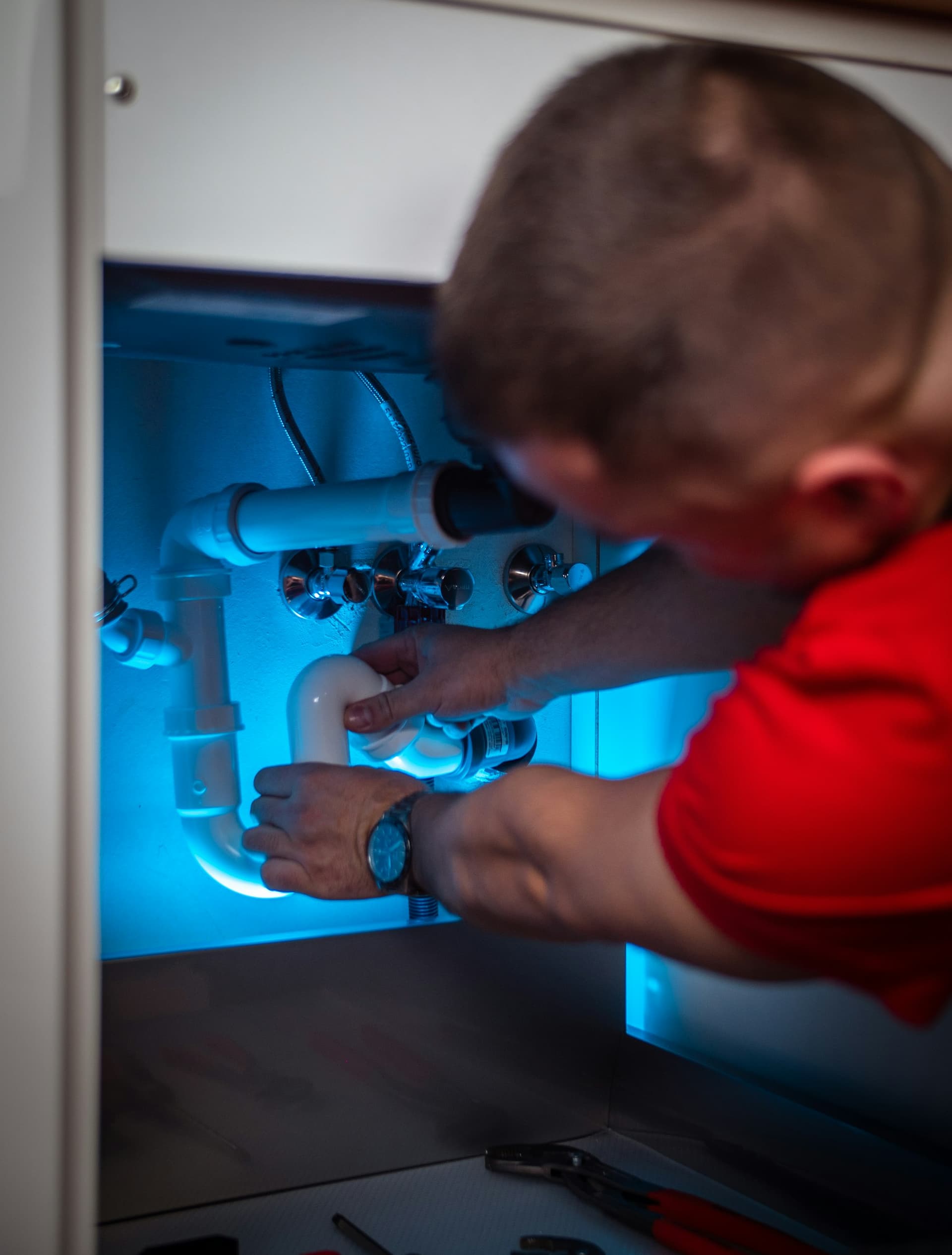 Usta lavabo altındaki tıkanmış sifonu söküyor
